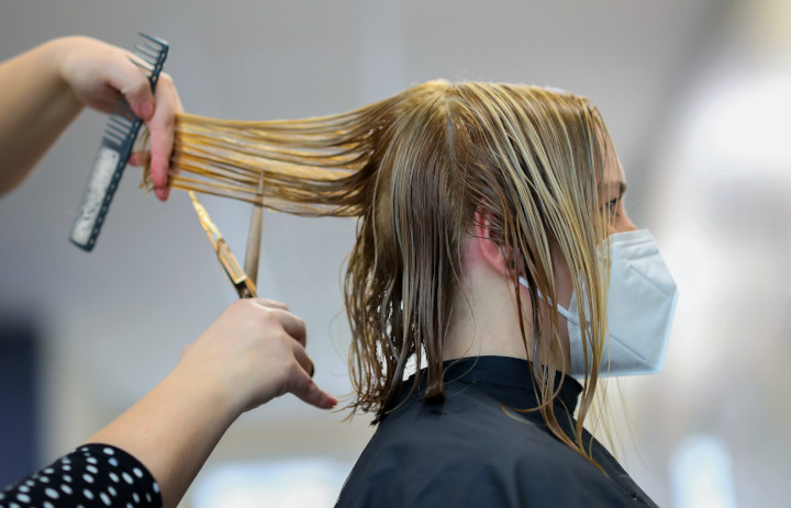 Imagem de uma cabeleireira cortando o cabelo de uma mulher.